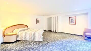 A bedroom with a bed, a chair, and two framed pictures on the wall.