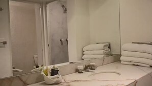 A bathroom with a marble sink, a mirror, and a towel rack with folded towels.