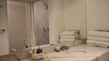 A bathroom with a marble sink, a mirror, and a towel rack with folded towels.