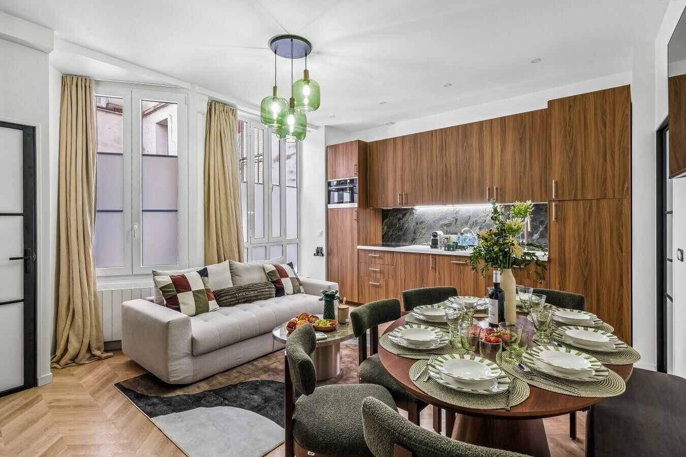 Ein modernes Wohnzimmer mit einer Couch, einem Esstisch für vier Personen und einer Küchenzeile mit Holzschränken und einer Marmorarbeitsplatte.