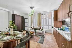 Ein modernes Wohnzimmer mit Sofa, Esstisch, der für eine Mahlzeit gedeckt ist, und einer Küchenzeile mit Schränken und Arbeitsfläche.