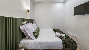 Ein modernes Hotelzimmer mit einem Bett, einem flachbildfernseher an der Wand und einer Heizung.