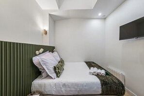 Ein modernes Hotelzimmer mit einem Bett, einem flachbildfernseher an der Wand und einer Heizung.
