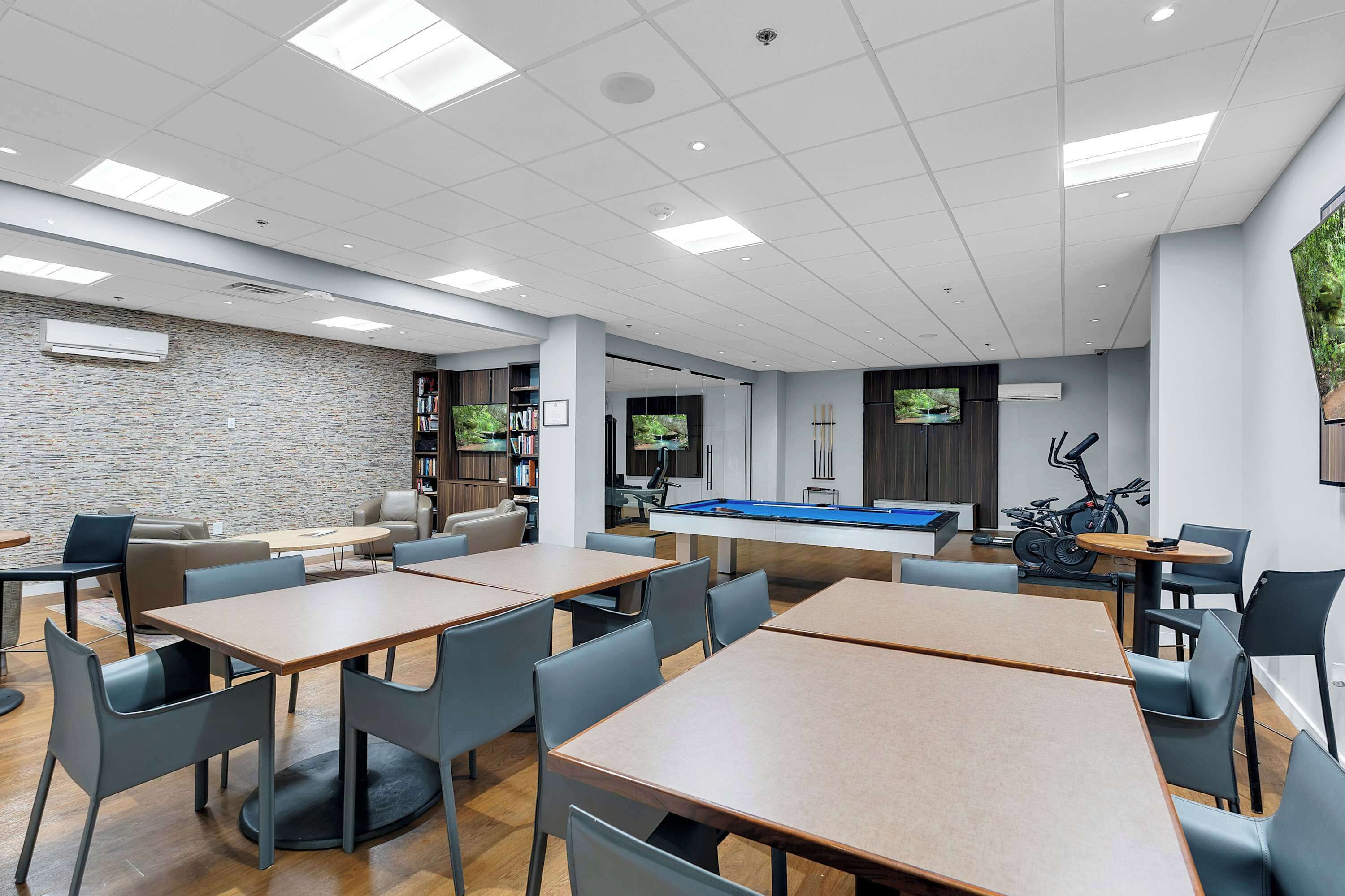 Un espacio interior moderno con mesa de billar, zona de estar y equipo de ejercicio.