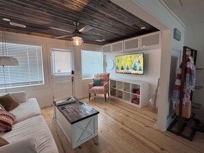 A living room with a sofa, coffee table, and a television mounted on the wall. - Cozy renovated 2-bedroom/1 bath cottage only 1 block from the beach! (Folly Beach)