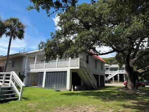 Uma casa de dois andares com telhado vermelho, varanda frontal e escada que leva ao segundo andar.