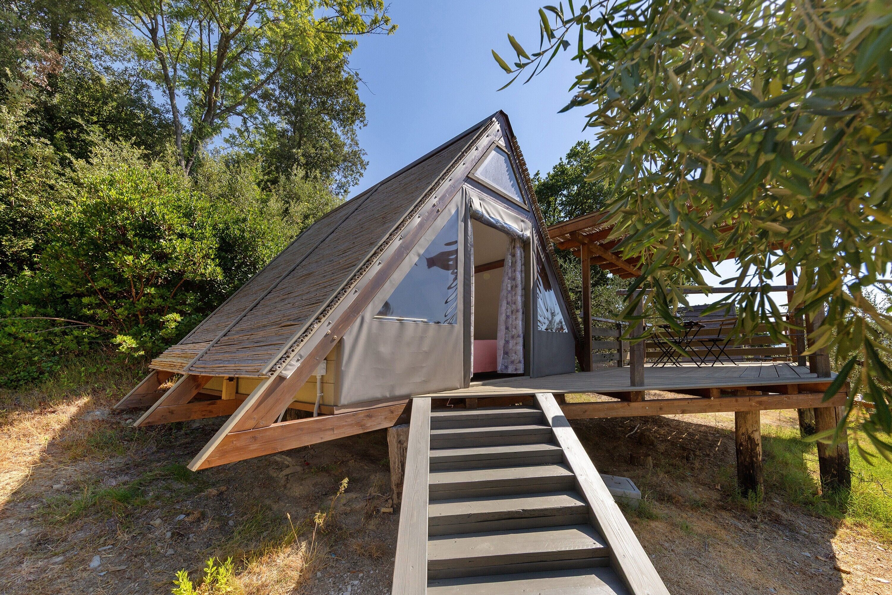 Una piccola struttura triangolare in legno con un ingresso coperto e un pontile di legno che vi conduce.