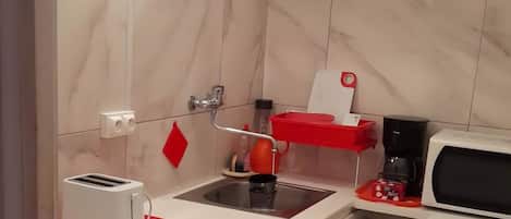 A compact kitchen with a washing machine, a microwave, and a toaster.