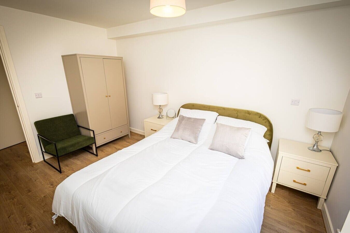 A bedroom with a bed, a wardrobe, a chair, and bedside tables.