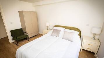 A bedroom with a bed, a wardrobe, a chair, and bedside tables.