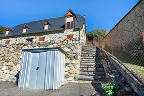 A stone building with a large garage door, a staircase leading up to a second level, and a chain-link fence. - "La Grange" Gîte with Mountain View and Wi-Fi (Artalens-Souin)