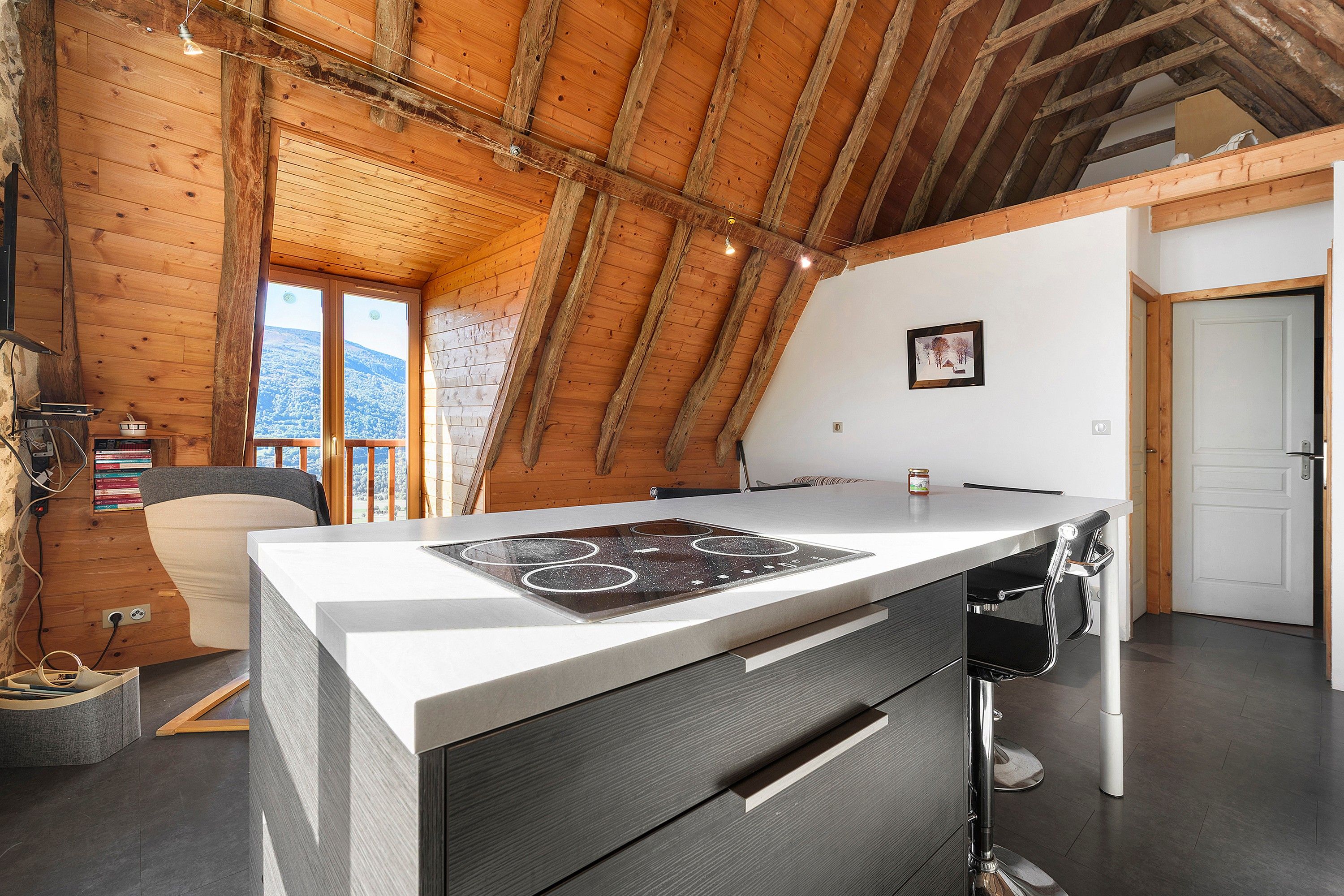 Una cucina moderna con soffitto in legno, piano cottura integrato e vista sull'esterno.