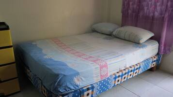 A bed with a patterned bedspread, pillows, and a headboard.