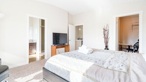 Une chambre moderne avec un grand lit, une télévision, un bureau et une chaise.
