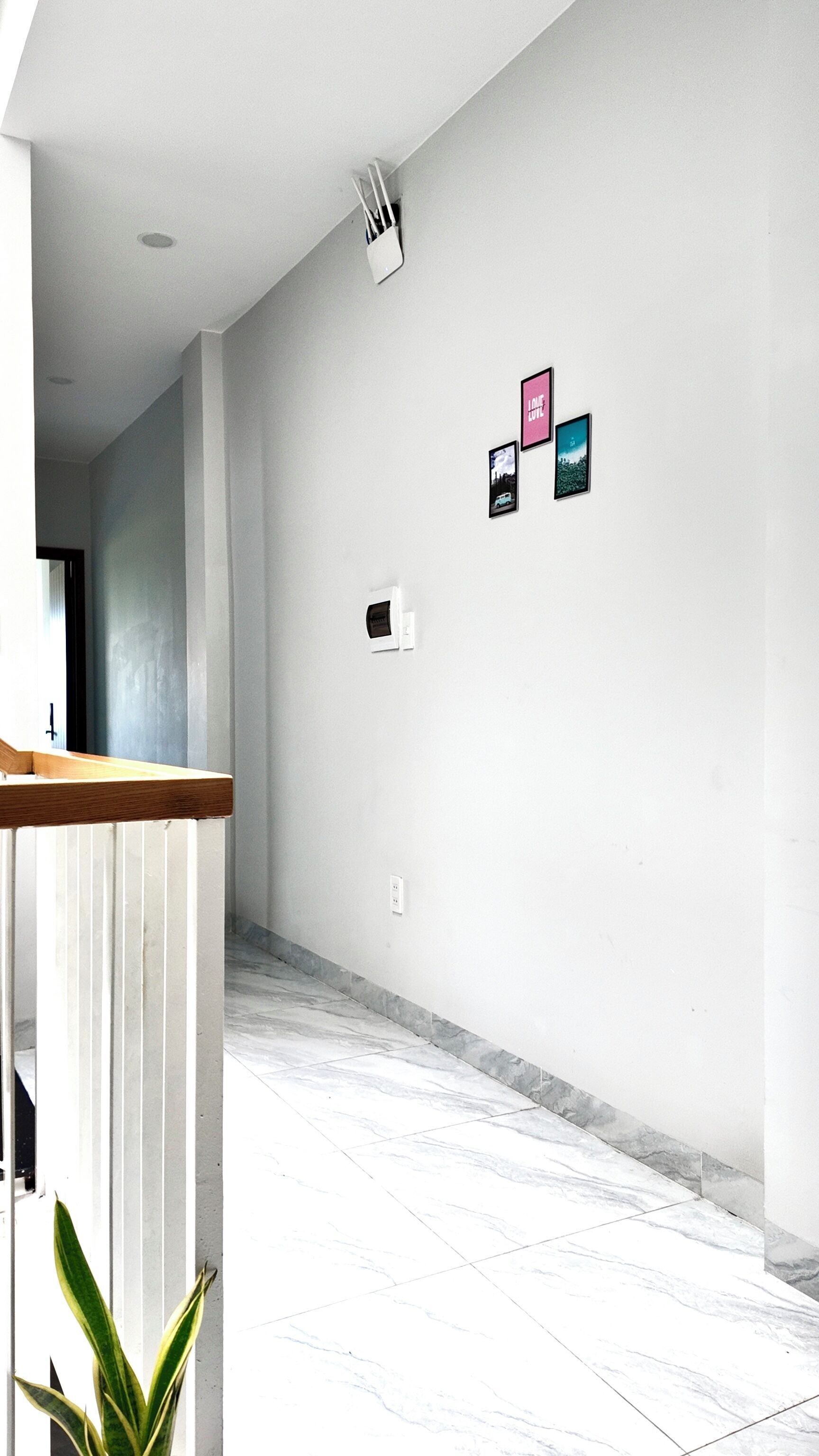 Un pasillo con pared blanca, un banco de madera y una planta en maceta.