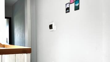 Un pasillo con pared blanca, un banco de madera y una planta en maceta.