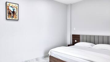 Een slaapkamer met een bed, nachtkastje, hoofdeinde en een lijst met kunstwerk aan de muur.