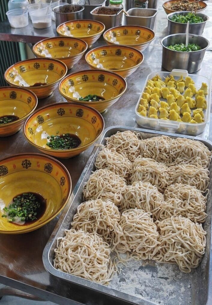 A variety of food items including bowls of noodles and sauces, and a tray of dumplings.