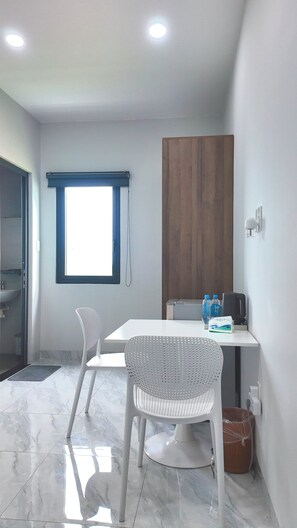 Habitación moderna con mesa de comedor, dos sillas, panel de madera, ventana y una lámpara en el techo.