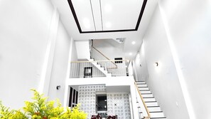 Un interior moderno con una escalera que sube a un piso superior, paredes blancas y un diseño decorativo en la parte inferior.