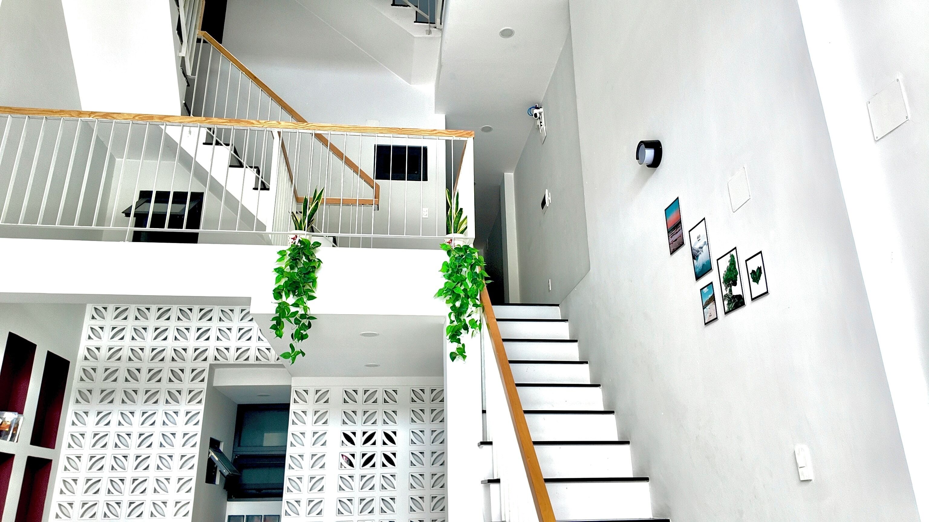 Un interior moderno con una escalera, paredes blancas y un elemento decorativo con diseño.