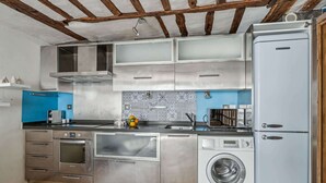 Eine moderne Küche mit Edelstahlgeräten, einem Einbauofen, einer Waschmaschine und einer blauen Spritzschutzwand.