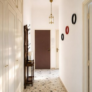 Ein Flur mit Tür, Lampe, Spiegel und Wandringen.