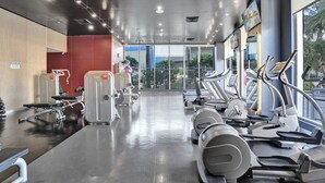 Et fitnesscenter med løbebånd, styrkemaskiner og et spejl.