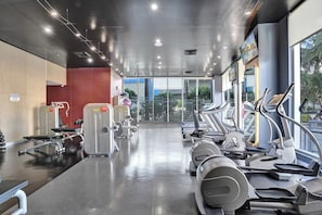 Ein Fitnessstudio mit Laufbändern, Kraftgeräten und einer Spiegelwand.