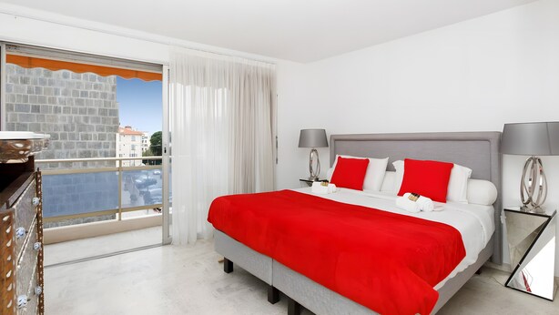 Een hotelkamer met een bed, twee nachtkastjes, een raam met gordijnen en uitzicht op gebouwen.