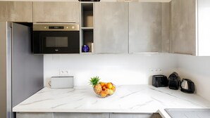 Een moderne keuken met een marmeren aanrecht, een ingebouwde oven, een broodrooster en een schaal met fruit.