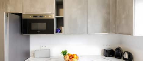 A modern kitchen with a marble countertop, a built-in oven, a toaster, and a fruit bowl.