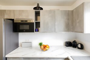 Eine moderne Küche mit Marmorarbeitsplatte, integriertem Backofen, Toaster und Obstschale.