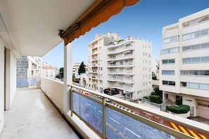 A balcony with a view of multi-story buildings, a clear sky, and a road with vehicles. - Apartment '3 Pièces Cannes' with Shared Terrace, Wi-Fi and Air Conditioning (Cannes)