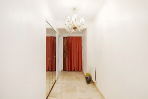 A hallway with a chandelier, red curtains, and a radiator. - Apartment '3 Pièces Cannes' with Shared Terrace, Wi-Fi and Air Conditioning (Cannes)