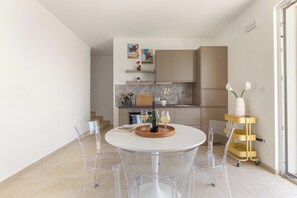 Eine moderne Küche mit Essbereich, ausgestattet mit einem runden Tisch, Stühlen, einer Weinflasche und Gläsern.