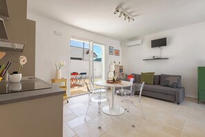 Un espai de viure modern amb cuina, zona de menjador i sofà.