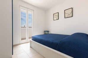 Un dormitori amb un llit, una nitzeta i una finestra amb vistes.