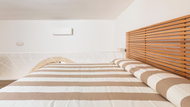Une chambre à coucher avec un lit, une tête de lit en lattes de bois et un motif géométrique sur le mur.