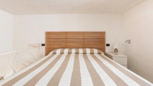 Une chambre à coucher comprenant un lit, une table de chevet, une lampe et un panneau de commande fixé au mur.