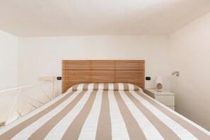 Ein Schlafzimmer mit Bett, Nachttisch, Lampe und einem an der Wand montierten Bedienfeld.