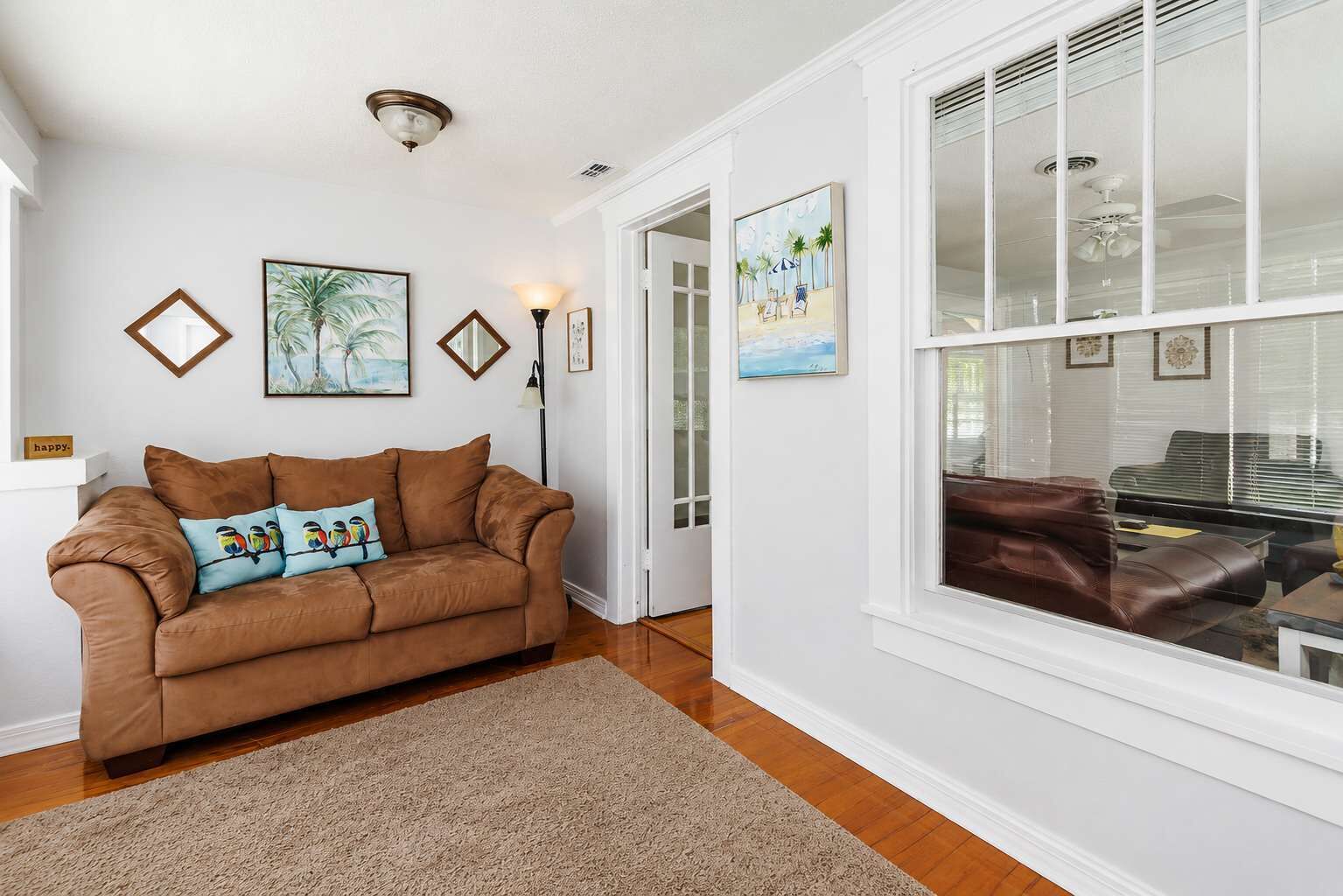 A living room with a brown leather sofa, a beige rug, and framed artwork on the walls.