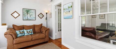 A living room with a brown leather sofa, a beige rug, and framed artwork on the walls.