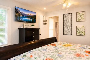 A bedroom with a bed, a dresser, a painting, and a ceiling fan. - 3BR Home | Prime Lake Hollingsworth | Dog Friendly (Lakeland)