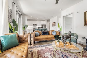 A modern living room with a sofa, a coffee table, and a decorative horse statue. - Modern 2BR Haven with Balcony & Open Living (Austin)