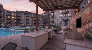 A poolside area with lounge chairs, a bar, and a grill. - Modern 2BR Haven with Balcony & Open Living (Austin)