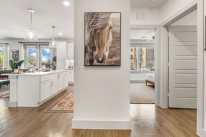 A modern kitchen with white cabinetry, a dining area with a table and chairs, and a large window with a view of the outside. - Modern 2BR Haven with Balcony & Open Living (Austin)