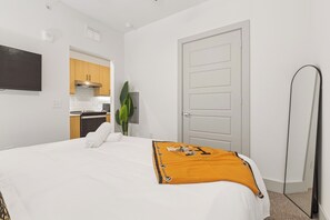 Ein Hotelzimmer mit einem Bett, einem Flachbildfernseher, einer Küchenzeile und einer Tür.
