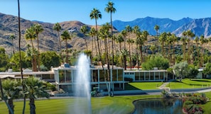 A modern building with a fountain, surrounded by palm trees and mountains. - Upscale 2-Bedroom + Den Condo in the Beautiful Seven Lakes Golf & Country Club (Palm Springs)