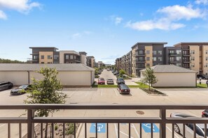 A parking lot with multiple cars, a clear sky, and modern apartment buildings in the background. - Relaxed 1BR Apartment Stay at The Nelson TNS 4204 (Austin)